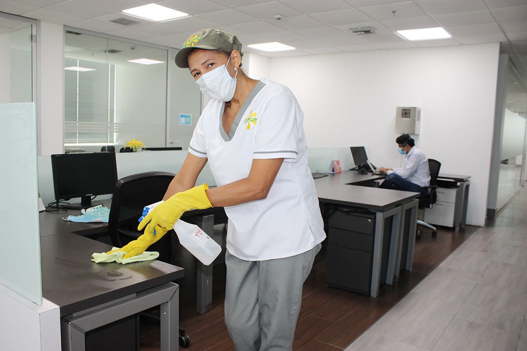 Colaboradora de Florecer desinfectando puestos de trabajo en una oficina corporativa